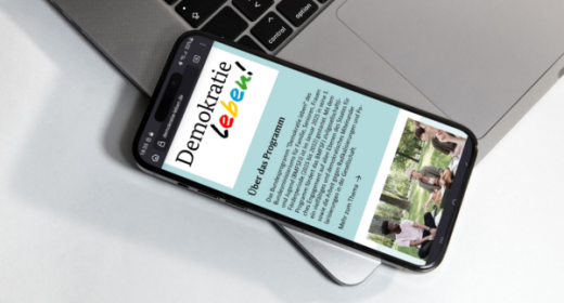 Demokratie leben-Webseite auf Handy auf Laptop, (c)BMFSFJ/AlgorithmWatch