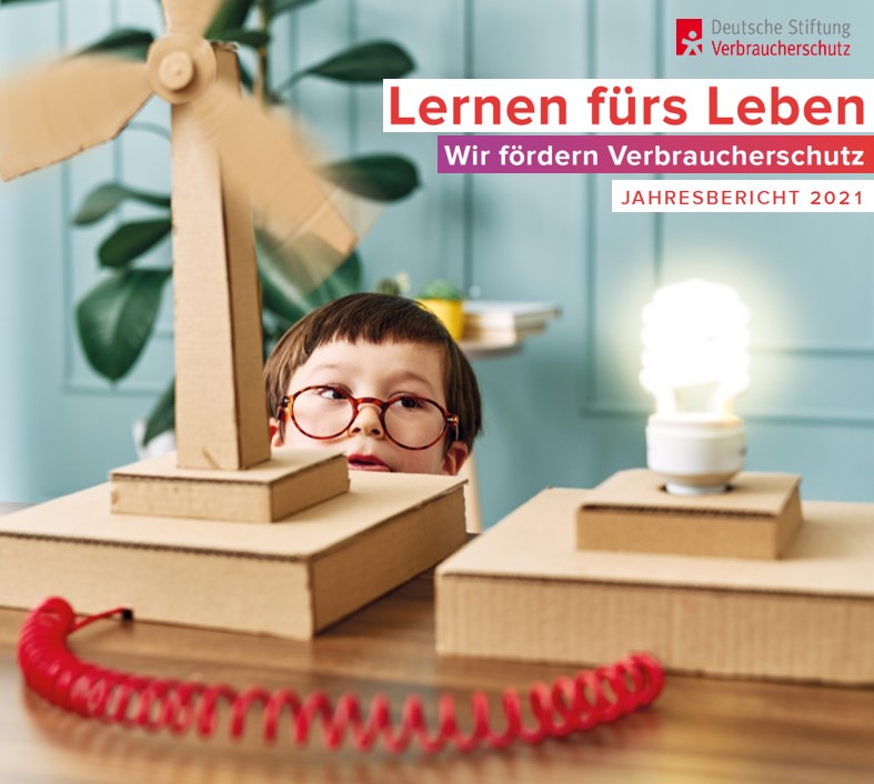 Cover Jahresbericht 2021: Junge steht hinter Papp-Windrad