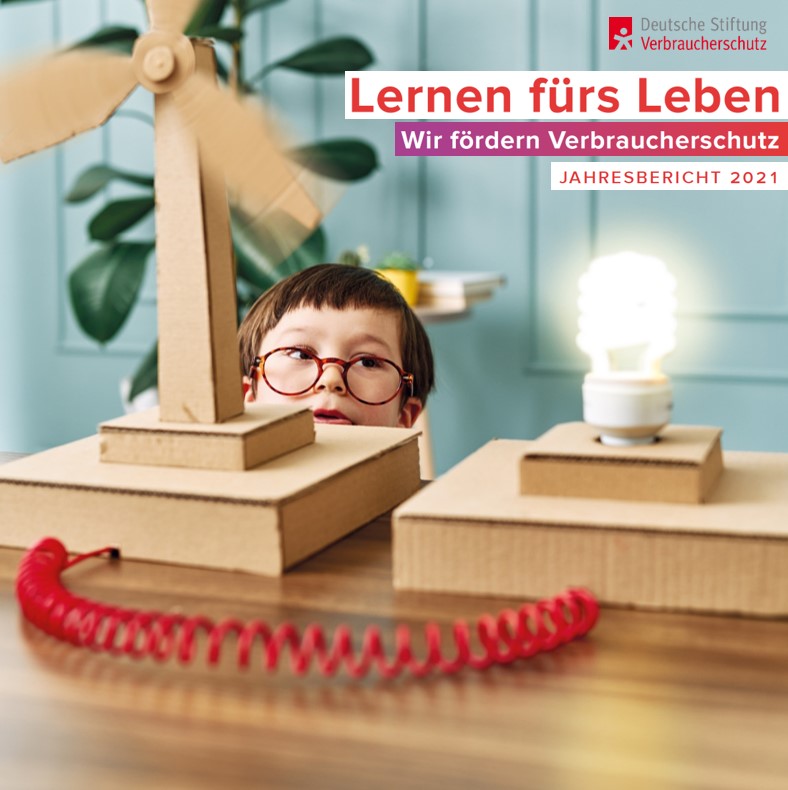 Cover Jahresbericht 20221: Junge steht hinter Papp-Windrad