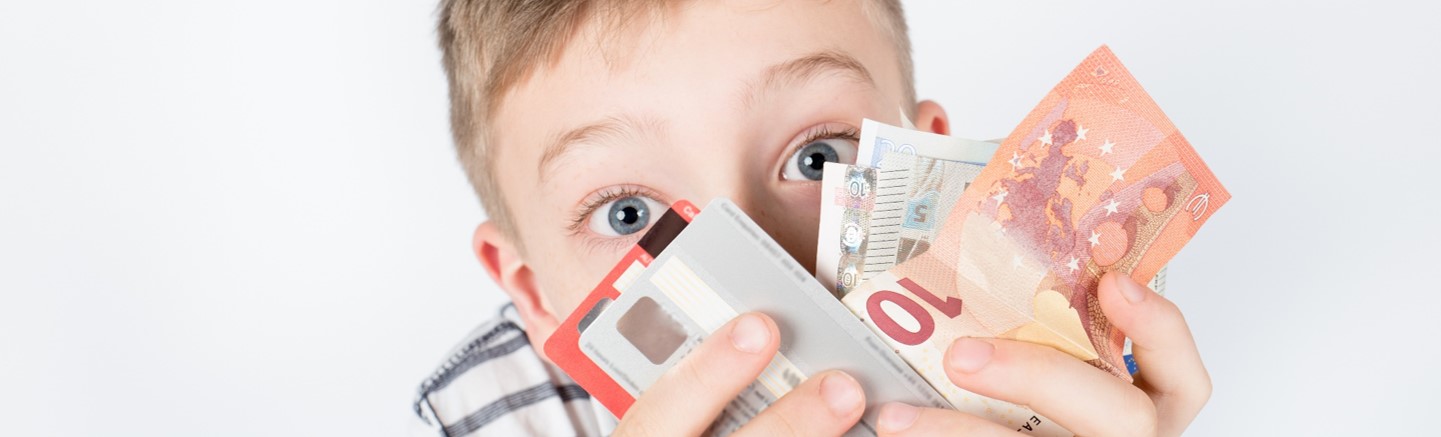 iStock.com/Eva Foreman Junge hält Geldscheine und Kreditkarten in den Händen
