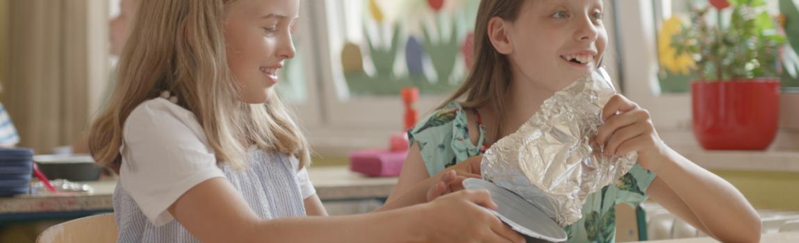 zwei Mädchen packen Essen as Alufolie aus