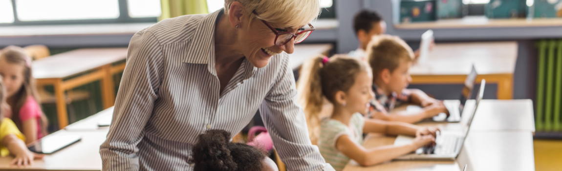 Lehrerin hilft Grundschülerin am Laptop