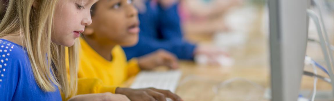 junge Mädchen sitzen an Computern in einem Klassenzimmer