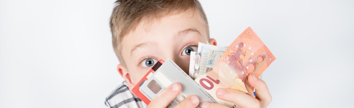 kleiner Junge hält Geldscheine und Kreditkarten in den Händen
