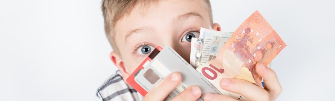 iStock.com/Eva Foreman Junge hält Geldscheine und Kreditkarten in den Händen