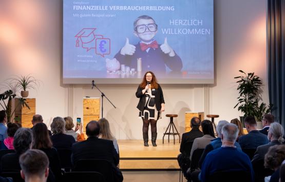 Julia Marg eröffnet das Dialogforum Finanzielle Verbraucherbildung auf der Bühne